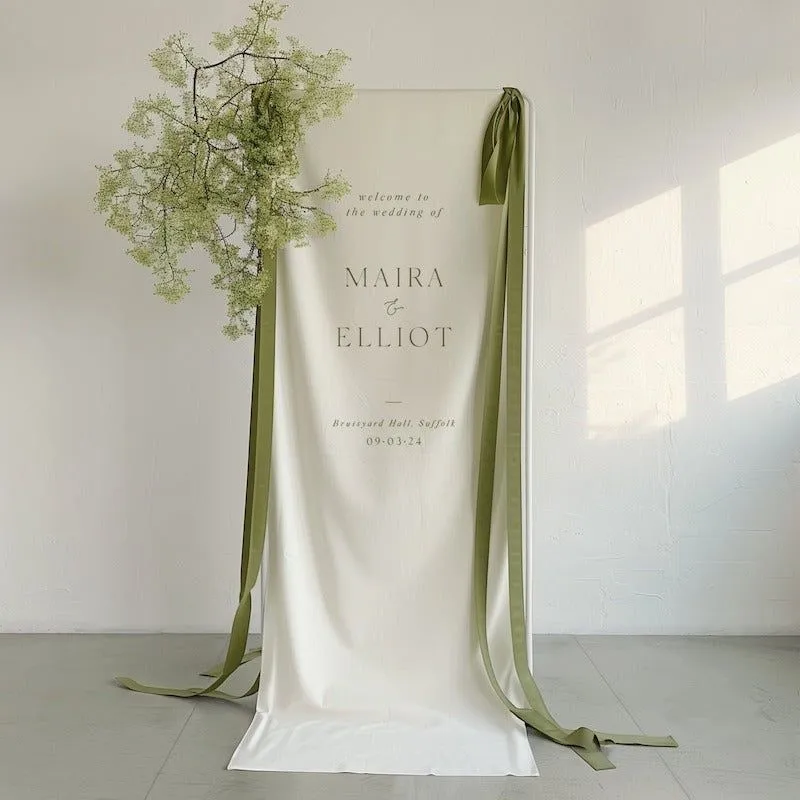 A hanging fabric welcome banner tied with green ribbon